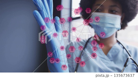 Pulling blue glove, health worker wearing mask and stethoscope in clinic, with pink hexagon network 135673637
