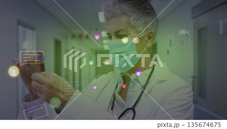 Viewing doctor tapping smartphone under hospital lights, with floating chat icons and stethoscope 135674675