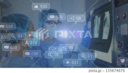 Reviewing scans surgeons wearing blue gowns standing in radiology room, with social media icons 135674678