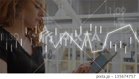 Red-haired woman in black top analyzing financial charts on tablet in glass office, copy space 135674757