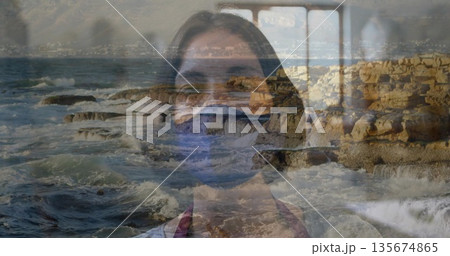 Gazing woman wearing protective face mask in room, with rocky shoreline and waves via window frames Gazing woman wearing protective face mask in room, with rocky shoreline and waves via window frames 135674865