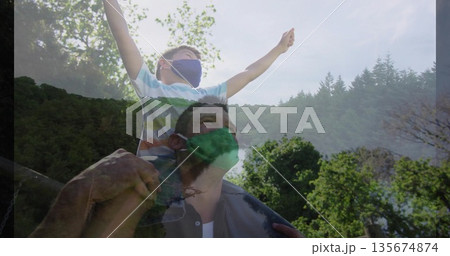 Riding boy stretching arms on shoulders of man on wooded hillside, with protective face masks Riding boy stretching arms on shoulders of man on wooded hillside, with protective face masks 135674874