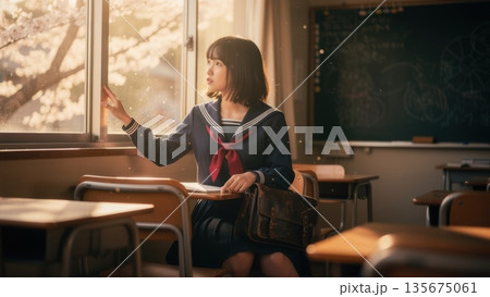学生鞄を抱え、想い出の詰まった教室で窓の外を見つめる女子高生 学生鞄を抱え、想い出の詰まった教室で窓の外を見つめる女子高生 135675061
