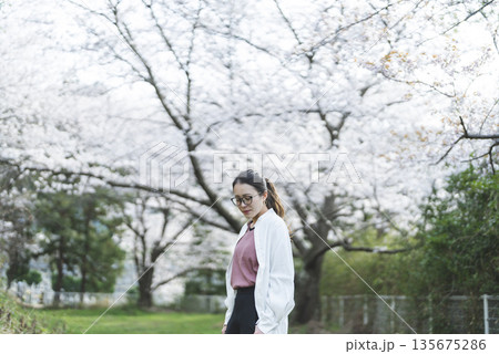 桜並木を散歩する若い女性 135675286