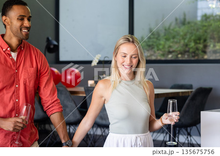Friends celebrating at home, holding champagne glasses and smiling joyfully Friends celebrating at home, holding champagne glasses and smiling joyfully 135675756