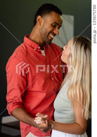 Couple dancing closely at home, sharing joyful smiles and tender moments 135675780