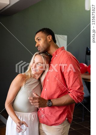 Happy couple celebrating at home, holding drinks and enjoying each other's company Happy couple celebrating at home, holding drinks and enjoying each other's company 135675827