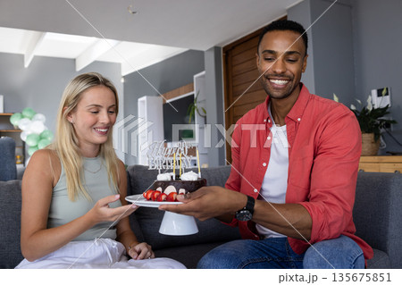 Smiling friends celebrating birthday at home, sharing cake and enjoying together 135675851