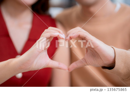 Close up hand heart shape of asian couple together in living room at home, showing love symbol. 135675865