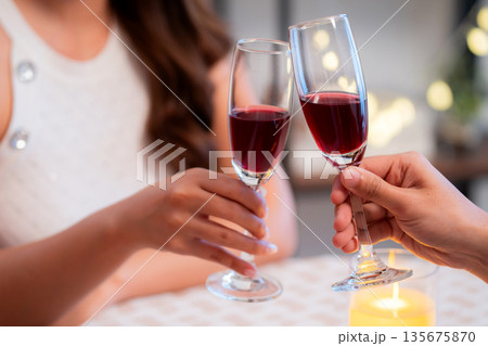 Happy asian couple clinking wine glasses during romantic dinner, celebrating Valentine's Day. 135675870
