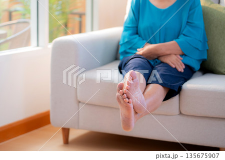 Close up leg senior woman practice stretch leg for treatment knee pain sitting on sofa. 135675907