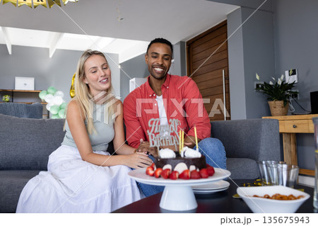 Couple celebrating birthday at home with cake and joyful smiles Couple celebrating birthday at home with cake and joyful smiles 135675943