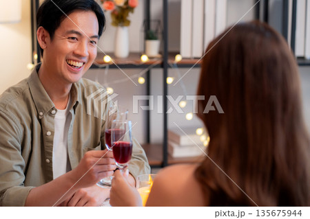 Happy asian couple clinking wine glasses during romantic dinner, celebrating Valentine's Day. 135675944