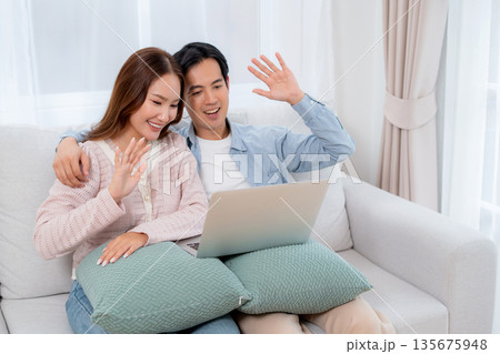 Happy asian couple video call on laptop together in living room at home. Happy asian couple video call on laptop together in living room at home. 135675948