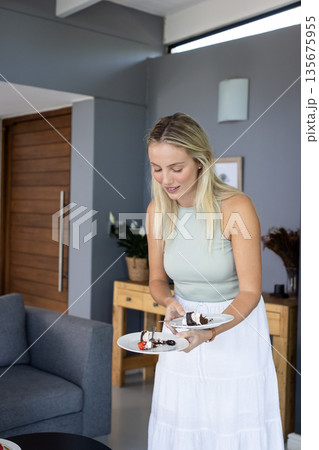 Woman serving dessert on plates at home, preparing for celebration 135675955