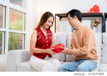 Happy asian man giving heart gift box to girlfriend celebrating Valentine's Day or anniversary. Happy asian man giving heart gift box to girlfriend celebrating Valentine's Day or anniversary. 135675965