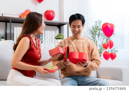 Romantic asian couple giving and receiving heart gift box for celebrating birthday or holiday. 135675969