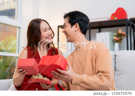 Romantic asian couple giving and receiving heart gift box for celebrating birthday or holiday. 135675970