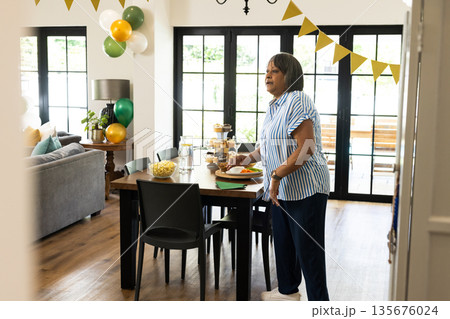 Woman preparing festive table with snacks and drinks for home celebration Woman preparing festive table with snacks and drinks for home celebration 135676024