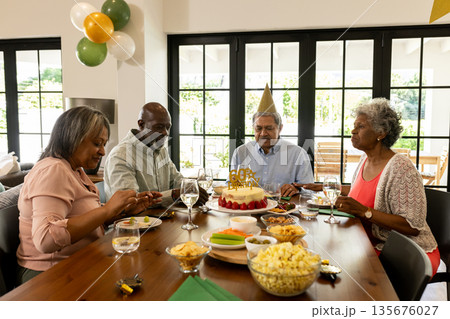 African American family celebrating birthday at home with cake and party hats African American family celebrating birthday at home with cake and party hats 135676027