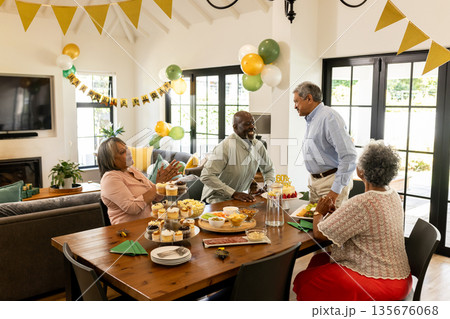 African American family celebrating birthday at home, enjoying cake and decorations African American family celebrating birthday at home, enjoying cake and decorations 135676068
