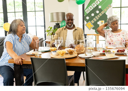 Celebrating retirement, African American seniors sharing food and laughter at home Celebrating retirement, African American seniors sharing food and laughter at home 135676094