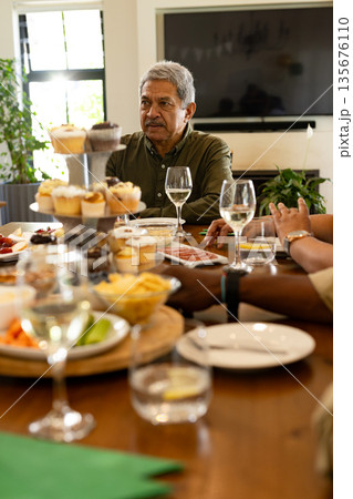 Family enjoying festive meal together at home, sharing laughter and conversation 135676110