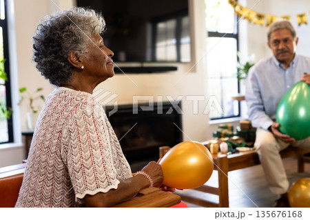 Elderly woman holding balloon, enjoying celebration with family at home 135676168