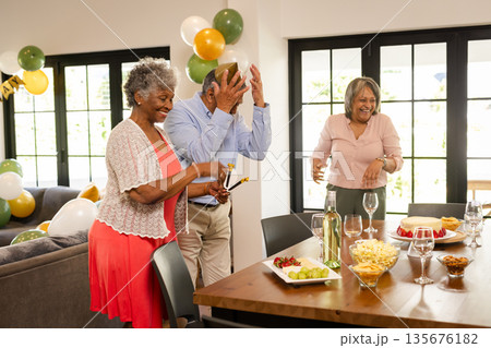 Seniors joyfully celebrating at home with food, drinks, and festive decorations 135676182
