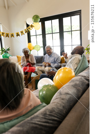 Family celebrating birthday at home, laughing and enjoying conversation on sofa 135676211