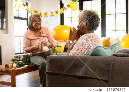 Inflating balloons, senior women preparing for celebration, smiling in living room 135676265