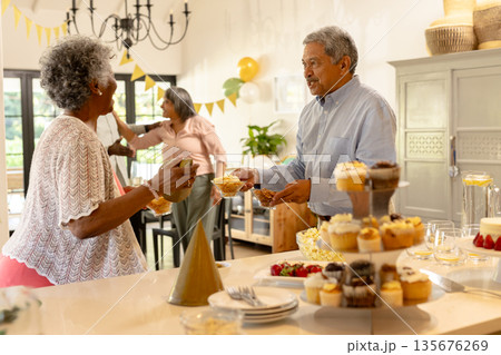 Elderly couple enjoying festive celebration with cupcakes and decorations at home Elderly couple enjoying festive celebration with cupcakes and decorations at home 135676269