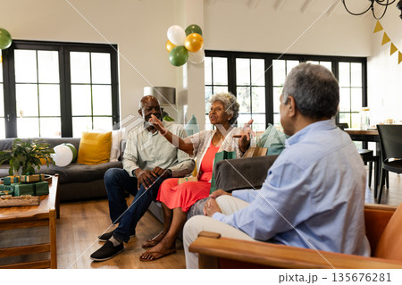 Elderly friends enjoying conversation and laughter at home during festive gathering 135676281