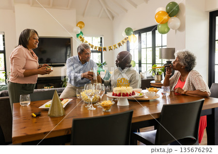 Family celebrating birthday with cake and gifts in cozy living room setting 135676292