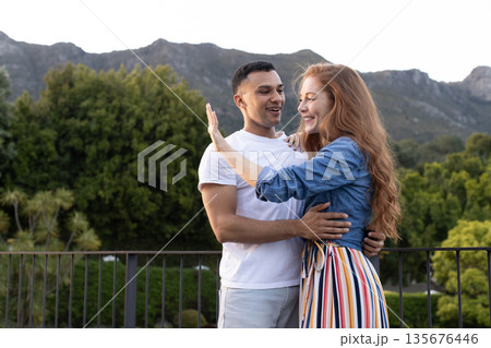 Young couple embracing outdoors, smiling and enjoying scenic mountain view 135676446