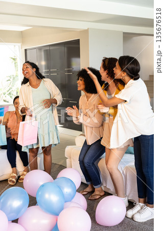 African American women celebrating with balloons and gift bags, smiling and clapping 135676518
