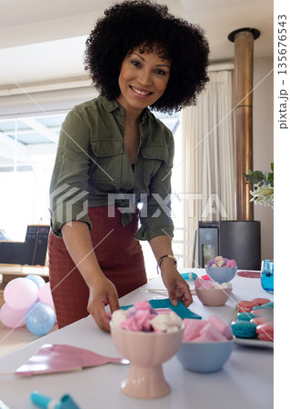 Smiling woman arranging colorful table decorations for festive celebration at home 135676543