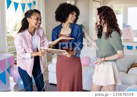 Women celebrating at home, exchanging gifts and smiling in festive atmosphere 135676559