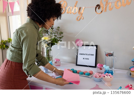 Woman preparing baby shower decorations, arranging table with pink and blue napkins Woman preparing baby shower decorations, arranging table with pink and blue napkins 135676600