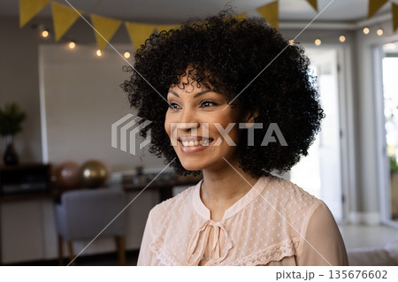 Smiling woman enjoying festive celebration at home with decorative lights Smiling woman enjoying festive celebration at home with decorative lights 135676602