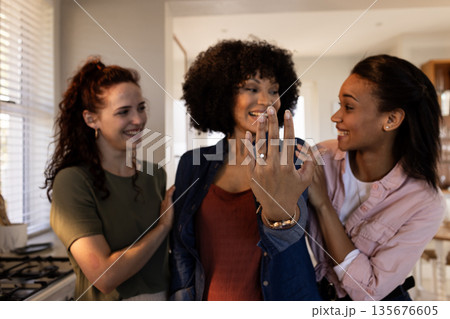 Friends celebrating engagement, woman showing ring with joy and excitement at home 135676605