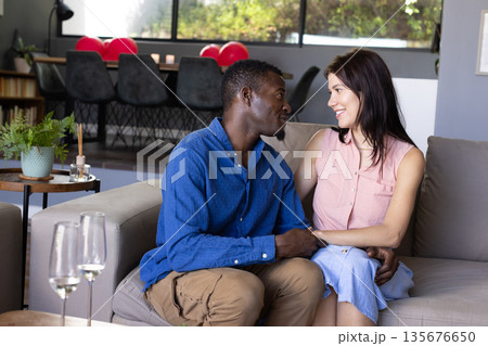 Couple sitting on sofa at home, sharing loving moment and smiling warmly Couple sitting on sofa at home, sharing loving moment and smiling warmly 135676650