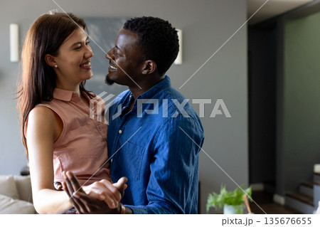 Couple embracing and smiling at home, enjoying joyful and intimate moment together 135676655