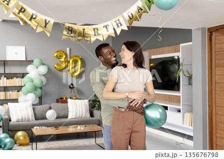 African American man and woman celebrating birthday at home, smiling and embracing African American man and woman celebrating birthday at home, smiling and embracing 135676798