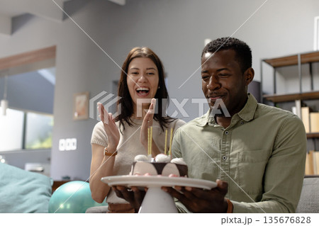 Celebrating birthday, happy couple enjoying cake with candles at home 135676828