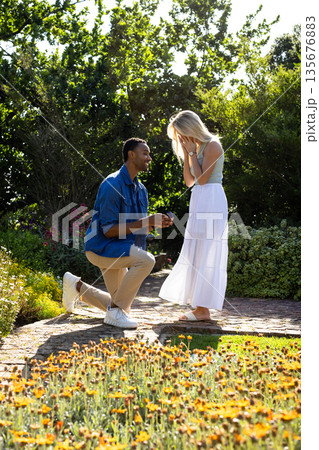 Man proposing to surprised woman in garden, surrounded by blooming flowers 135676883