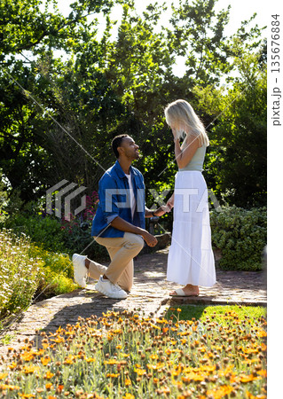 Man proposing to surprised woman in beautiful garden surrounded by flowers 135676884