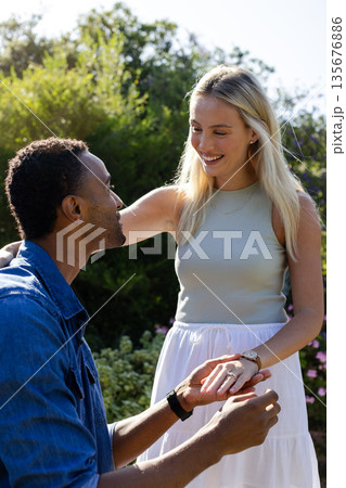 Man proposing to smiling woman in garden, holding engagement ring Man proposing to smiling woman in garden, holding engagement ring 135676886