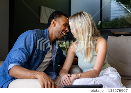 Couple laughing and enjoying quality time together on cozy living room sofa 135676907