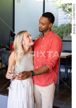 Couple celebrating at home, holding champagne glasses and smiling at each other Couple celebrating at home, holding champagne glasses and smiling at each other 135676931